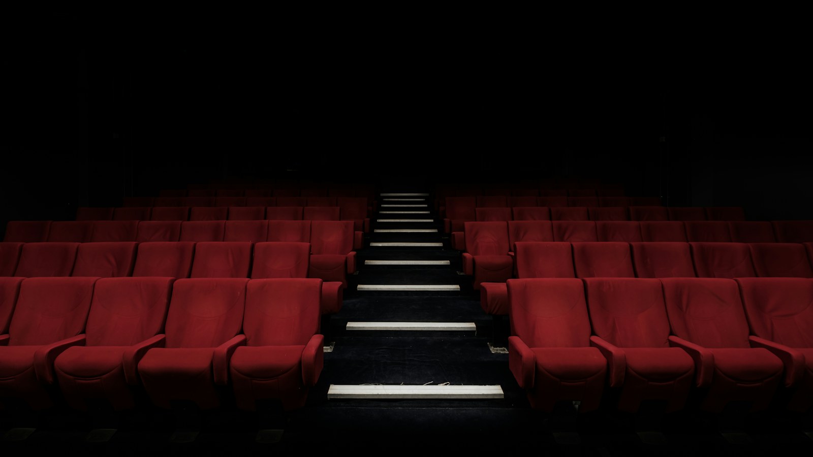 Rows of red seats in a darkened movie theater